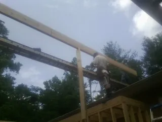 Carpenter setting a ridge beam over a new addition frame — Ice Dam Removal by Roofing Brothers in Lawsonville