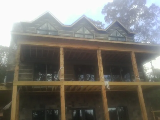 Dormers and porch framing on a large log home under construction — Roof Coating work by our crew in Lawsonville
