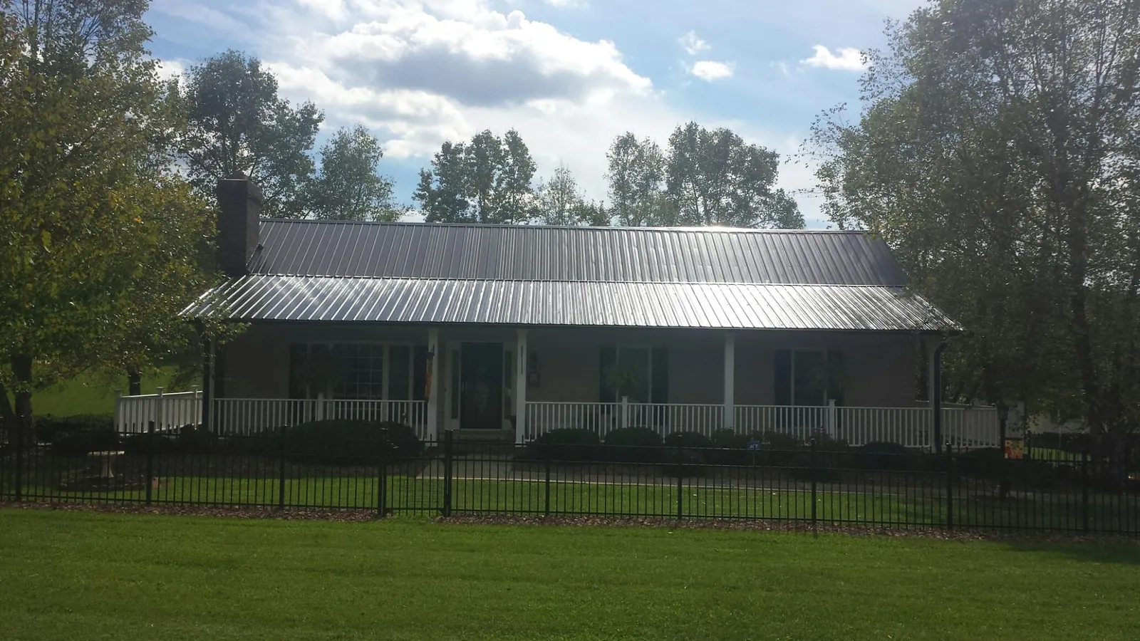 Gray metal roof on a brick ranch with a full width front porch — Gutter Guard Installation work by our crew in Lawsonville