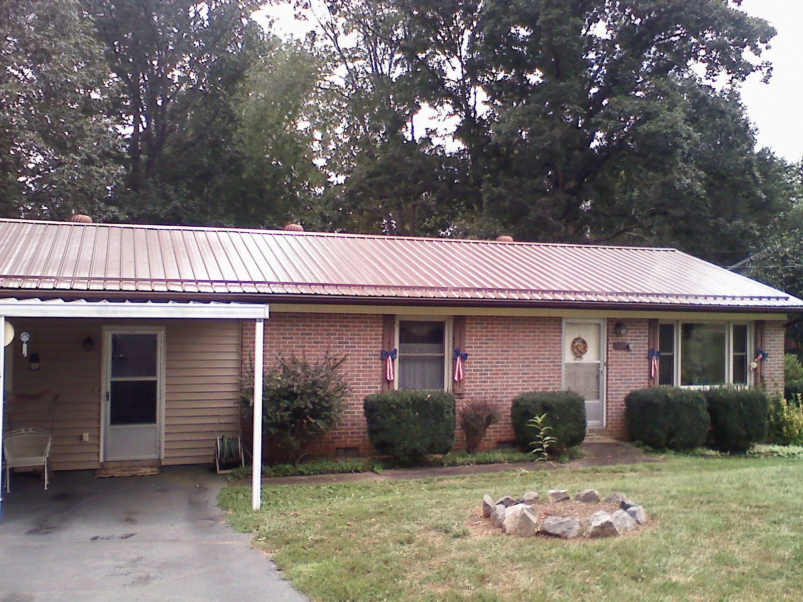 Bronze metal roof and carport on a brick ranch home — Roof Repair work by our crew in Lawsonville
