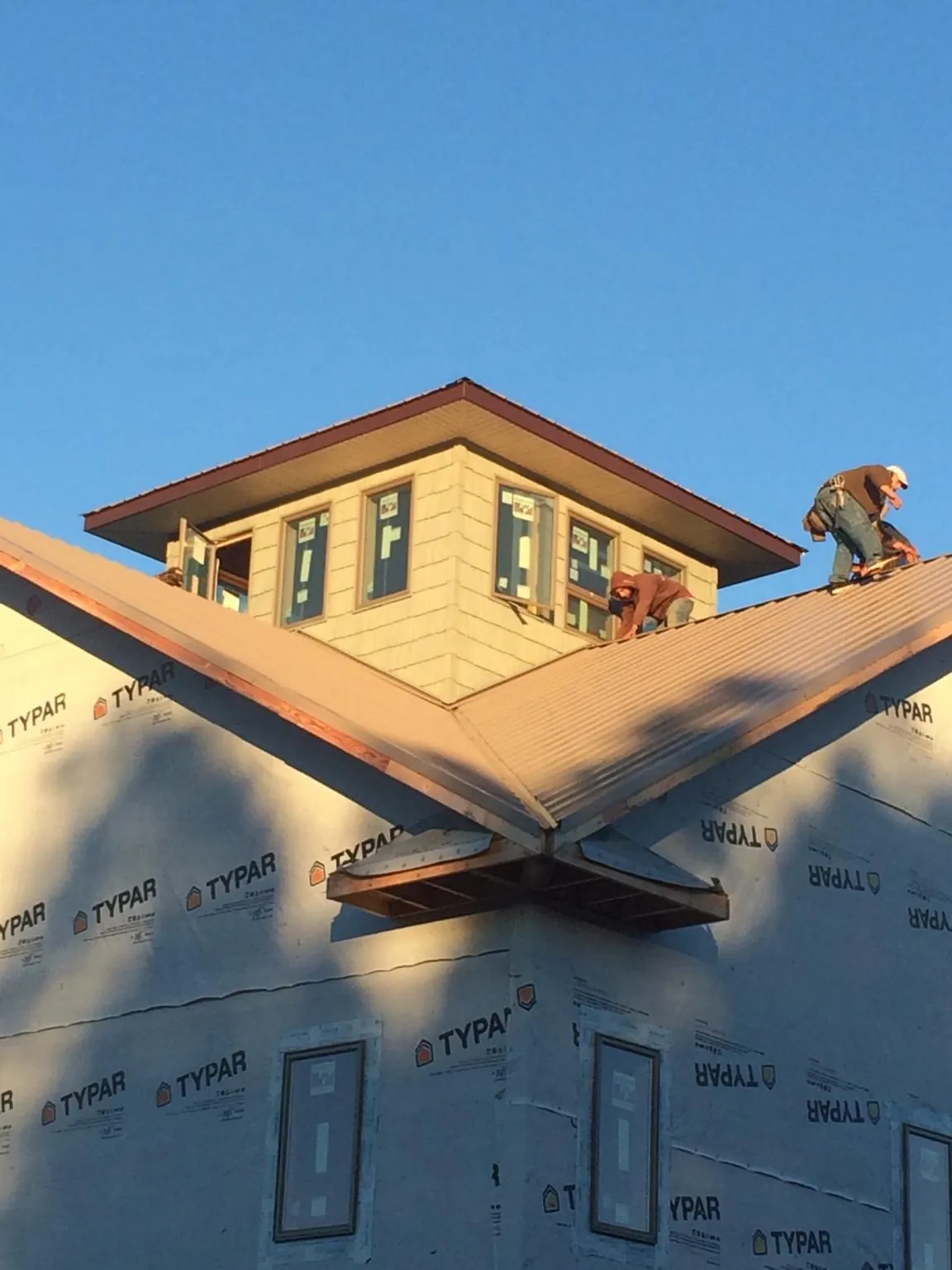 Roofers working around a rooftop cupola on a new metal roof at sunset — Roof Waterproofing in Lawsonville by Roofing Brothers